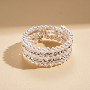 Detailed close-up of multi-layer spiral bracelet with white pearls and sparkling rhinestones