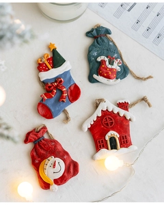 Detailed view of four resin Christmas ornaments including stocking, snowman, and cabin motifs