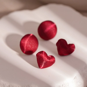 Vintage red fabric wrapped round and heart stud earrings set on white stone display