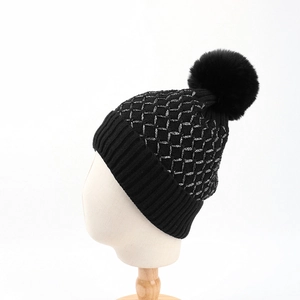 Black knit beanie with silver tinsel plaid pattern and faux fur pompom for winter warmth