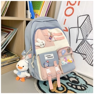 Detail of multi-pocket patchwork school backpack with cute plush pendants and badges