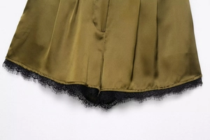 Detaillierte Nahaufnahme von dunkelolivgrünen Satin-Shorts mit zartem schwarzem Spitzenbesatz