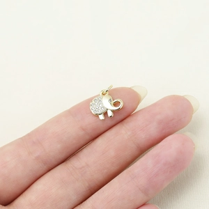 Detailed view of a gold elephant pendant with inset crystals held on a fingertip