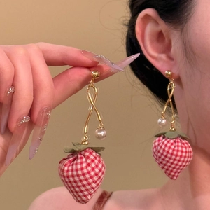 Macro view of strawberry earring featuring red plaid fabric and a white faux pearl