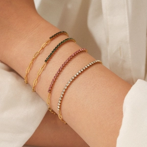 Macro shot of gold-plated stainless steel layered bracelets with colorful zircon stones on wrist