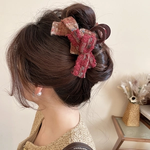 Detailed view of a red-brown tweed bow hair claw clip worn in a woman's hair