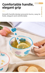 Detail of hand-painted floral ceramic mug with heart-shaped stirring spoon and blue rim