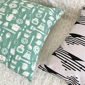 Close-up of cotton linen pillow covers with green kitchen pattern and abstract lines