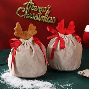 Velvet Christmas reindeer antler gift bag with red ribbon on festive background