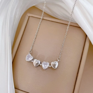 Dettaglio collana in argento con quattro cuori e zirconi lucenti su morbida seta bianca