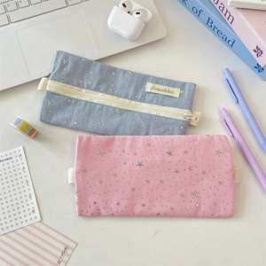 Detailed macro of fabric pencil cases with silver star patterns and yellow zippers