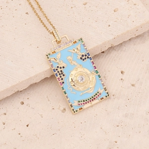 Macro view of gold tarot card necklace with blue enamel and colorful gemstone accents