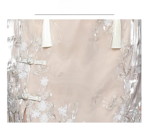 Detailed close-up of champagne satin fabric with flower embroidery and traditional frog button