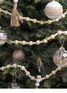 Close-up of Christmas wooden bead garland with tassels and snowmen on tree