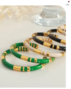 Detailed view of bamboo-style enamel bangles in green, beige and black gold plating