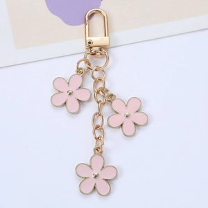 Colorful floral alloy keychain with three pink flower charms and golden chain on white background