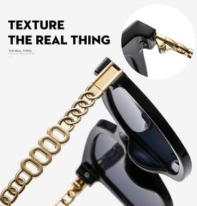 Detail of stylish black sunglasses showing golden chain temples and reinforced metal hinges