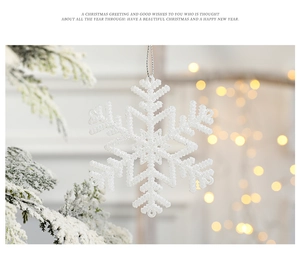 Sparkling white snowflake ornament hanging on a snowy branch with golden bokeh lights