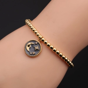 Details des goldenen Perlenarmbands mit Mond- und Sternenanhänger am Handgelenk