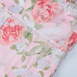 Close-up of pink floral print fabric with intricate white hollow lace trimming details