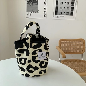 Detail of leopard print canvas tote bag on white table with minimalist lifestyle background