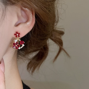 Detailed view of 18k gold plated earrings with red flower and heart-shaped gemstones