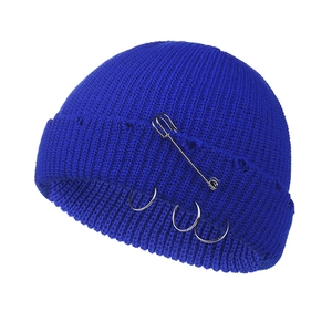 Detail of navy knit beanie with decorative silver safety pin and metal rings accessories