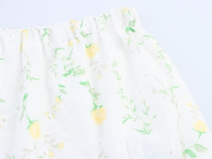 Dettaglio di gonna ricamata bianca con stampa floreale gialla e vita elastica traforata
