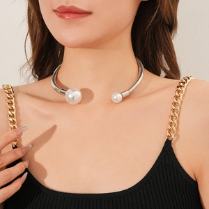 Detail shot of a silver metallic collar necklace featuring two white faux pearls on a model