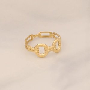 Macro detail of gold geometric hollow interlocking ring on light marble background
