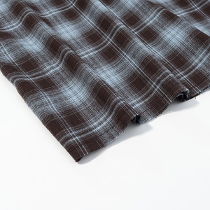 Detailed macro view of the dark brown and light blue plaid fabric with hem stitching