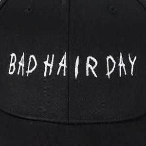 Primer plano del bordado blanco BAD HAIR DAY en la gorra de béisbol de algodón negro