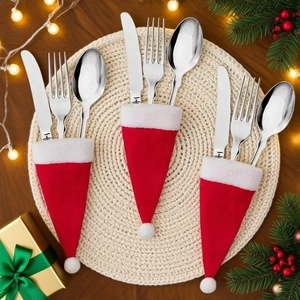 Set of 3 mini Christmas hat cutlery holders on a festive wooden table with pine decorations