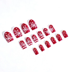 Christmas press-on nails featuring red base with white snowflake and gold star patterns