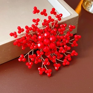 Detailed view of handmade red crystal flower brooch with gold wire weaving and pearls