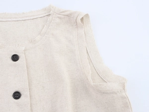 Detail of beige linen sleeveless top showing raw edge texture and black round buttons
