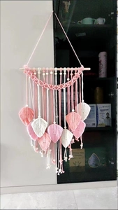 Close-up of pink and white macrame feathers with wooden beads on a boho wall hanging