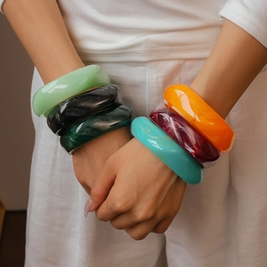 Detailed view of colorful marbled resin geometric square bangles on model hands