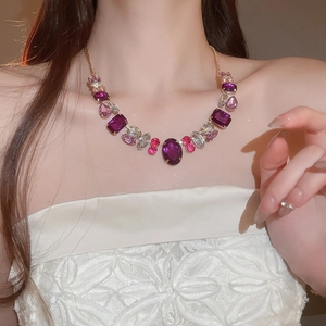 Close-up of vintage gold necklace with purple and pink crystal pendants on model neck