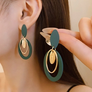 Macro shot of retro geometric butterfly drop earrings in dark green and gold finish