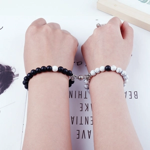 Close-up of matte black and white turquoise magnetic heart bracelets for couples