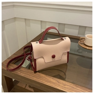 Detailed close-up of retro apricot and dark red patchwork leather bag on wood surface