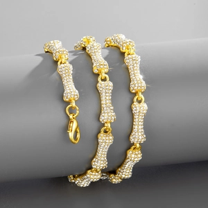Close-up of golden bone-shaped chain link necklace with iced out crystal rhinestones