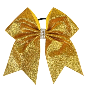 Close-up of gold glitter hair bow with silver rhinestone center and black elastic band