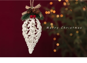 Close-up of white cutout pinecone ornament with red berries and a rustic twine hanger