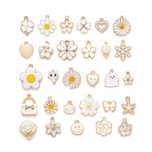 Flat lay of white enamel daisy and heart charms with gold-plated alloy borders