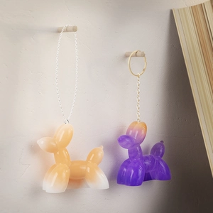 Detail of glossy gradient balloon dog keychains hanging on wooden hooks