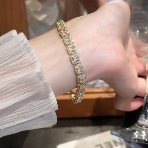 Vue macro détaillée d'un bracelet de luxe en or avec zircons carrés sur le poignet d'une femme