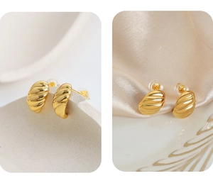 Macro detail of gold-plated twisted croissant earrings with classic metallic texture