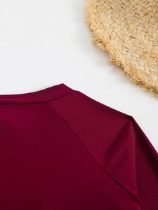 Détail de la texture du maillot de bain bordeaux avec un chapeau de paille de plage